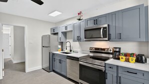 A modern kitchen with grey cabinets, stainless steel appliances, and a white countertop.