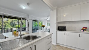 A modern kitchen with white cabinetry, a stainless steel sink, and a built-in microwave.