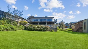 A modern two-story house with a large front lawn and a balcony.