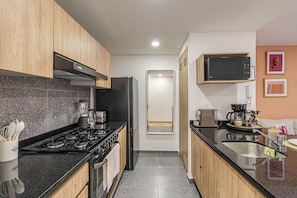 Una cocina moderna con estufa a gas, refrigerador, microondas y cafetera.