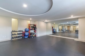 Un gimnasio con equipo de ejercicio, un espejo y un estante de mancuernas en la pared.