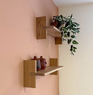 A wall with two wooden shelves, each holding decorative items and a potted plant.