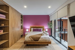 A modern bedroom with a wooden bed, a purple wall, and a large window.