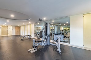 A modern gym with various exercise equipment, a mirrored wall, and a clean, spacious layout.