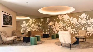 Een moderne lounge met banken, poefs en een bloemen behangmuur.
