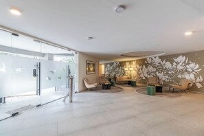 Un interior moderno con mostrador de recepción, zona de estar y un mural floral.