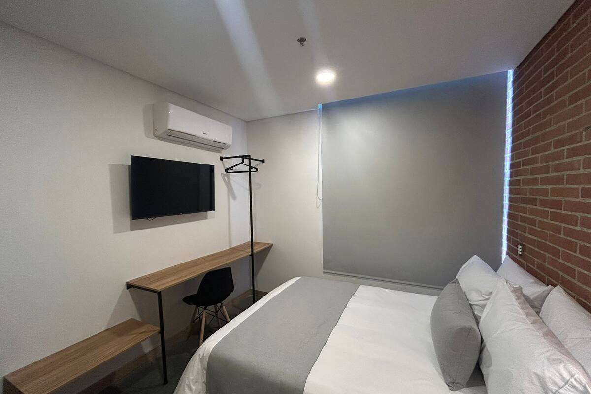 Een moderne hotelkamer met een bed, een bureau, een stoel, een televisie en een kledingkast.