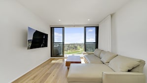 Uma sala de estar moderna com uma janela grande, um sofá e uma mesa de centro.