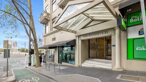 A hotel entrance with a glass canopy, a bike lane, and a sign for 'ONE EXHIBITION'. - Chic 1-bed Apartment In the Heart of Melbourne (Melbourne)