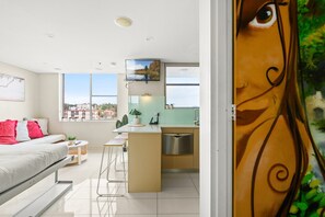 Un apartamento moderno con un dormitorio, kitchenette y un amplio ventanal con vistas a la ciudad.