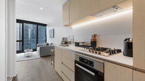 Une cuisine moderne équipée d’une cuisinière, d’un four et d’un évier intégrés. On y trouve également un coin repas avec un canapé gris et une petite table.