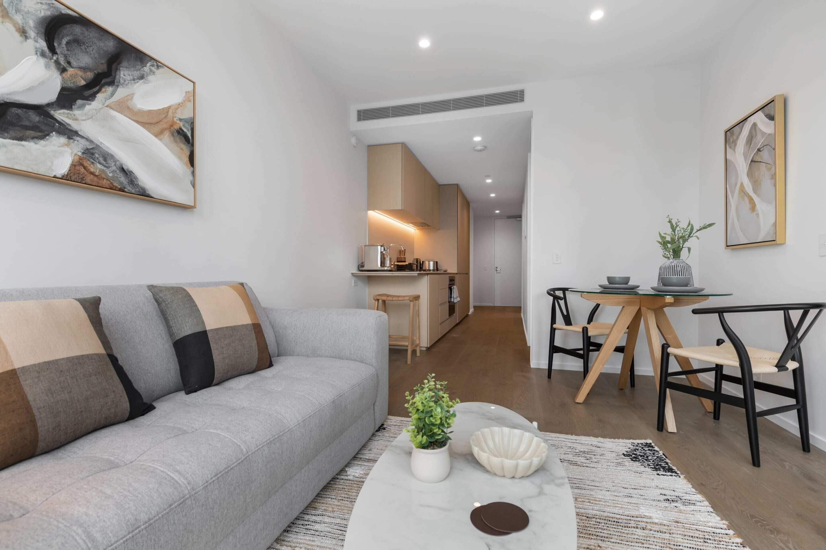 A modern living room with a grey sofa, a coffee table with decorative items, and a dining area with a small table and chairs.