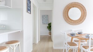 A dining area with a round wooden table, white chairs, and a large mirror on the wall.