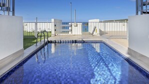 A modern swimming pool with clear blue water, surrounded by a white fence and a metal railing. - Stunning Ocean Views With Manly At Your Doorstep (Sydney)