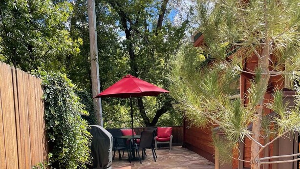 A patio with stone flooring, a wooden fence, and a red umbrella. - Christopher Creek Cabins - Cabin 2 (Christopher Creek)