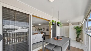 Una sala de estar moderna con un sofá gris, una mesa de comedor con un banco y plantas colgantes.
