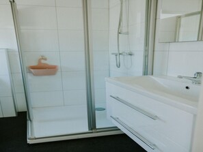 A bathroom with a glass shower enclosure, a white sink, and a mirror. - Comfortable Forest Lodge With Open Space (Balkbrug)