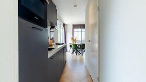A modern kitchen with a built-in stove, a dining area with a table and chairs, and a view of the outdoors through large windows. - Modern Chalet Near Beach in Renesse (Renesse)