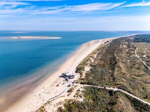 An aerial view of a beach with a sandy shore, a small building with a roof, and a road winding through the landscape. - Modern Chalet Near Beach in Renesse (Renesse)