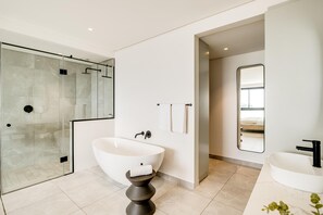 A modern bathroom with a glass-enclosed shower, a freestanding bathtub, and a white sink. - Ocean View 1bed Apartment in Sea Point Marlo Cove (Cape Town)