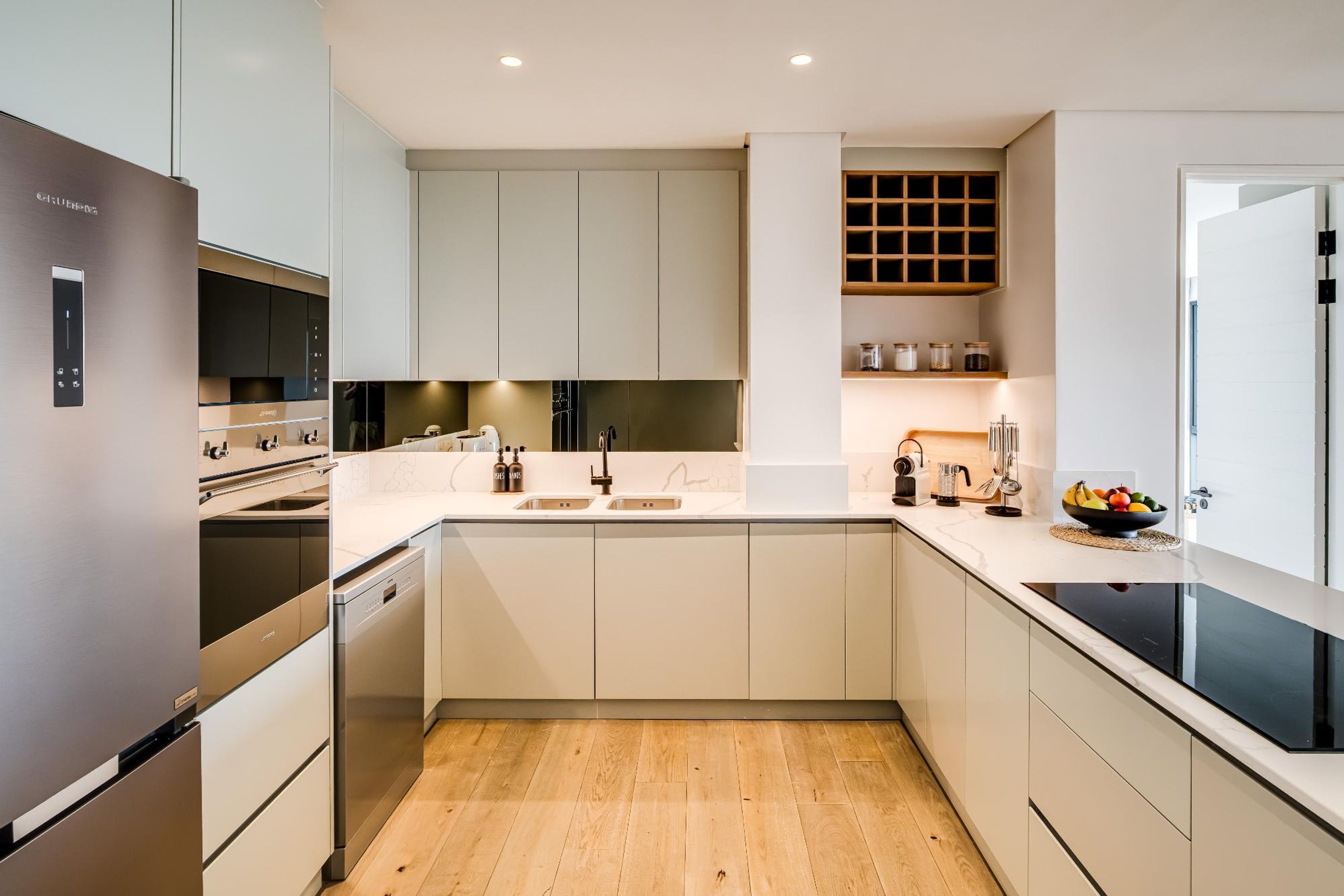 A modern kitchen with a built-in dishwasher, a double sink, and a black induction cooktop.