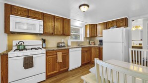 Une cuisine avec des meubles de rangement en bois, une cuisinière blanche, un four à micro-ondes, un lave-vaisselle et un réfrigérateur.