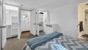 Une chambre à coucher comprenant un lit, un dressing et un espace douche.