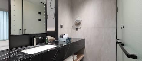 A modern bathroom with a black marble sink, a large mirror, and a glass shower enclosure.