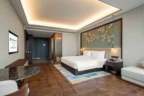 Ein Hotelzimmer mit Bett, Nachttisch, Lampe und Blick auf den Flur.