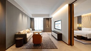 Una habitación de hotel moderna con sofá, mesa de centro, televisor y cama.