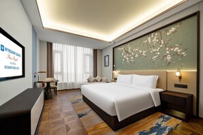 Une chambre d’hôtel équipée d’un lit, de tables de chevet, d’un bureau et d’un grand écran affichant des informations sur l’hôtel.