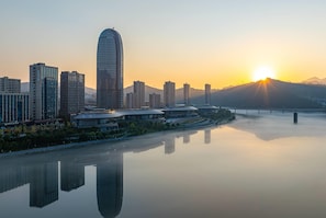 A cityscape with modern high-rise buildings and a calm river reflecting the structures. - Wyndham Grand Plaza Royale Milky Way Jiande (Hangzhou)
