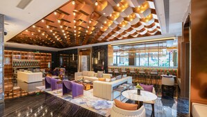 A modern lobby with a seating area, a bar, and a large window.