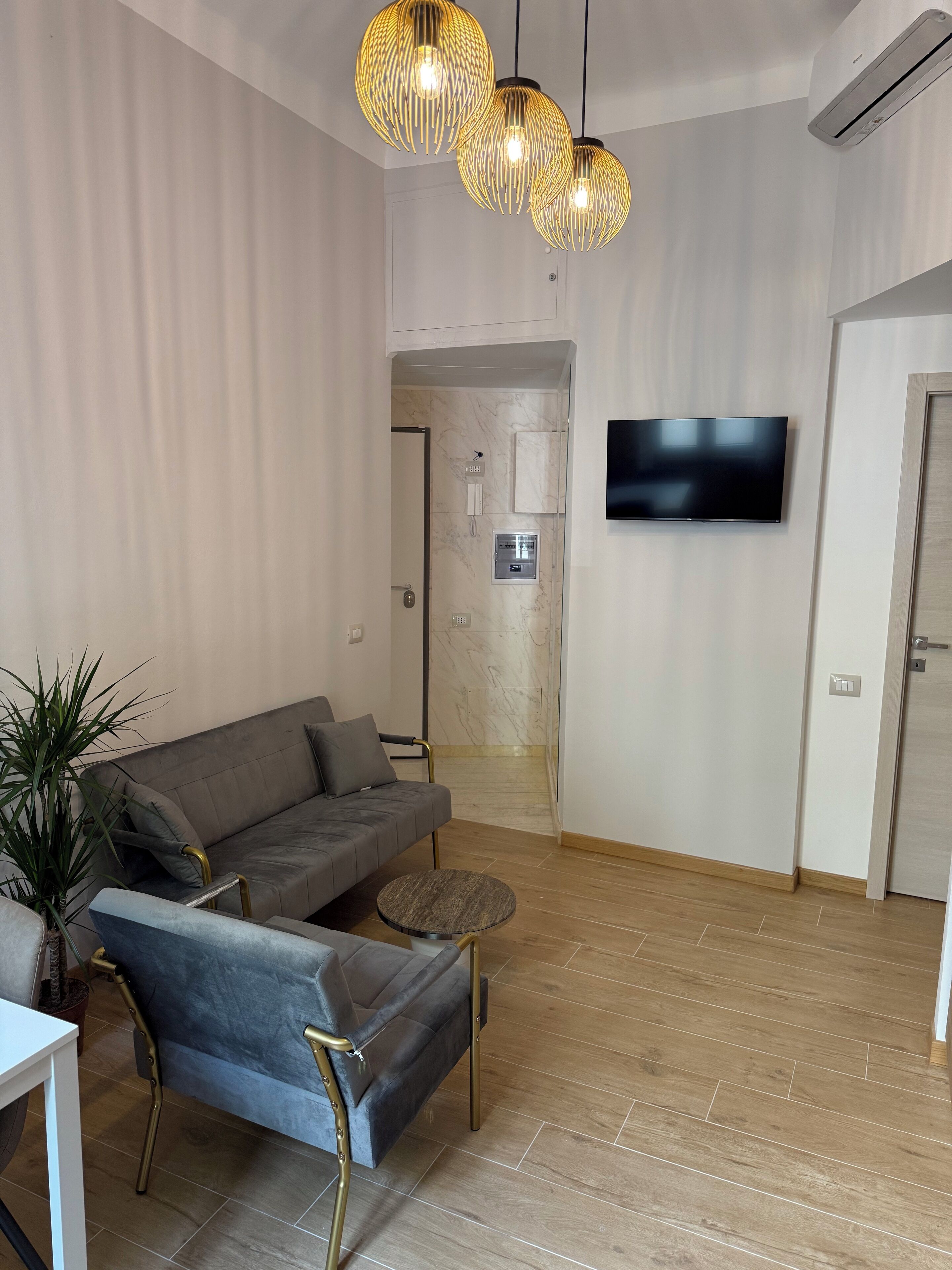 Ein modernes Wohnzimmer mit einer Eckcouch, einem kleinen runden Tisch und einem Blumentopf.