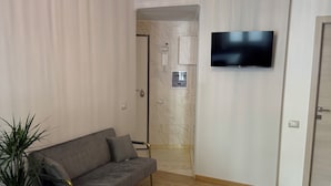 Ett modernt vardagsrum med en hörnsoffa, ett litet runt bord och en krukväxt.