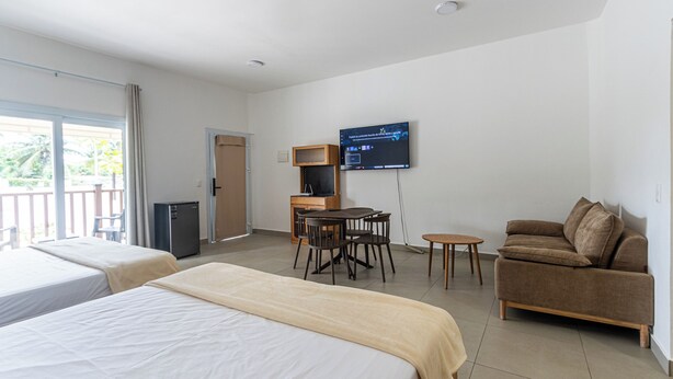 A hotel room with two beds, a sofa, a TV, a desk, and a balcony. - Laguna Park Apartments (Sosúa)
