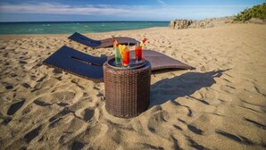 A beach with a wicker table holding colorful drinks and a blue mat. - Laguna Park Apartments (Sosúa)