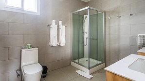 A modern bathroom with a glass-enclosed shower, a toilet, and a sink. - Laguna Park Apartments (Sosúa)