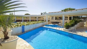 A swimming pool with a sunshade, surrounded by potted plants and a covered seating area. - Laguna Park Apartments (Sosúa)