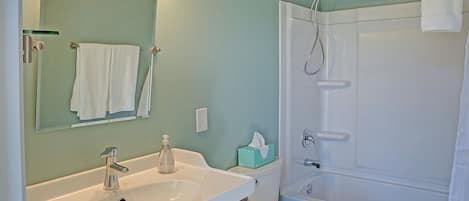 A bathroom with a sink, mirror, toilet, and shower.