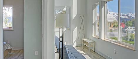 A modern interior with a bench, a lamp, and large windows offering a mountain view.