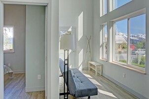 Un interior moderno con un banco, una lámpara y ventanas amplias que ofrecen vistas a la montaña.