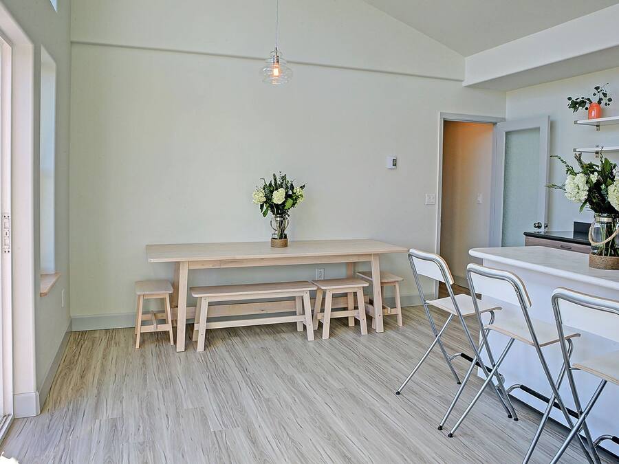 Una cocina moderna con una mesa y banco de madera, encimera blanca y una lámpara colgante.