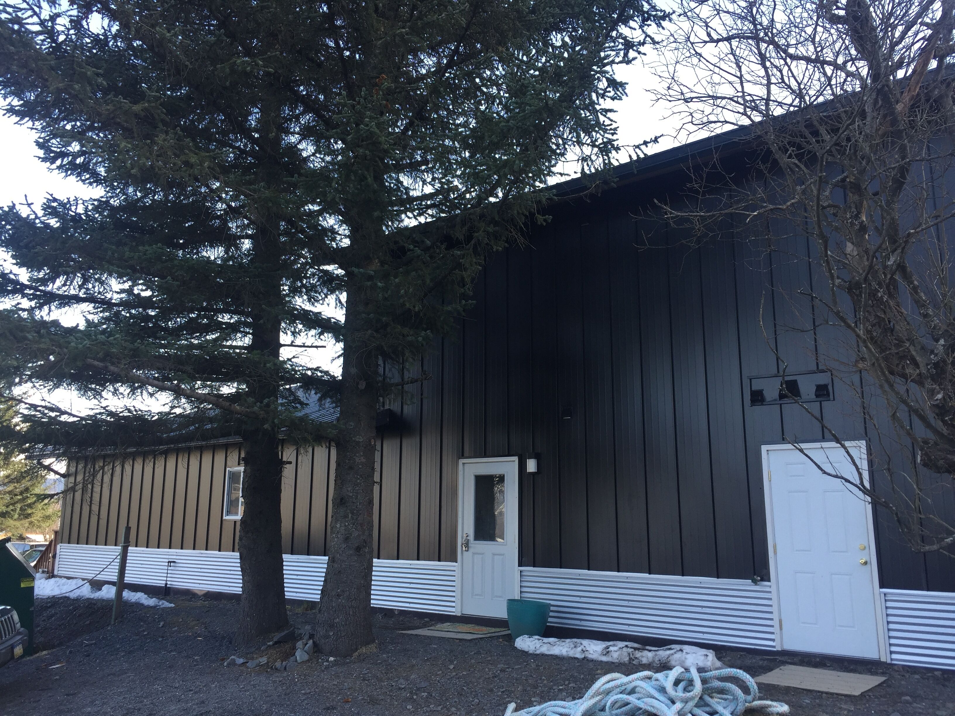 A building with a dark exterior, a white door, and a small porch area.