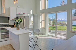 Cocina moderna con una isla grande, electrodomésticos de acero inoxidable y vistas a un paisaje montañoso a través de amplias ventanas.