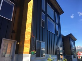 Un edificio de varios pisos con amplias ventanas, fachada de madera y cielo despejado.