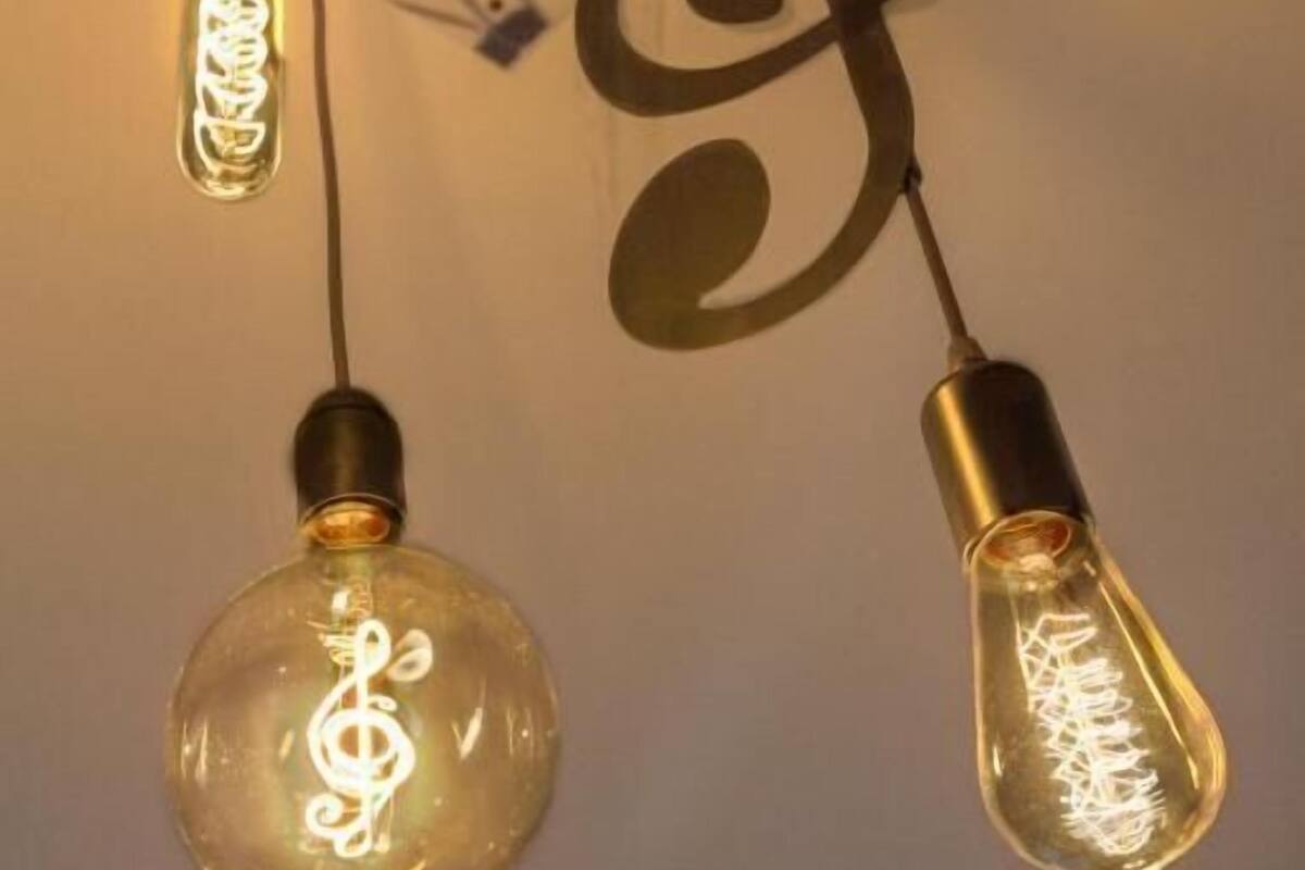 To lyseblus med et treble-g-nøgledesign indeni, hængende fra et loft med et krydsformet mønster.