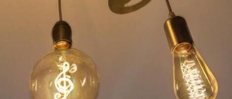Two light bulbs with a treble clef design inside, hanging from a ceiling with a crisscross pattern.