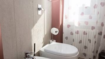 Un bagno con bidet, water e lavandino.