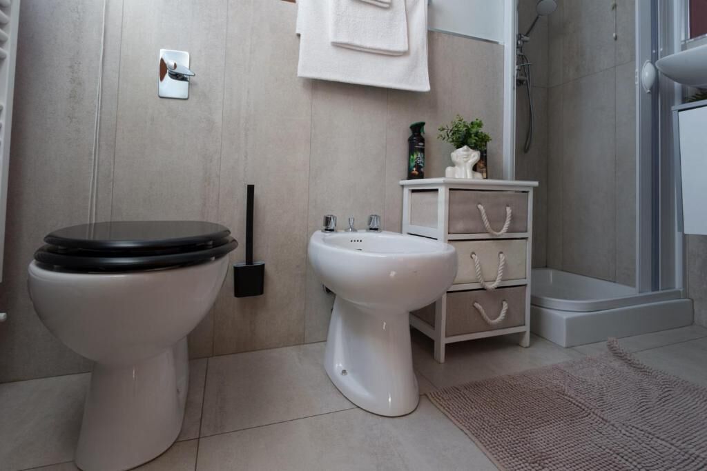 A bathroom with a toilet, bidet, and a small cabinet with drawers.